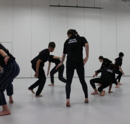 GCSE Dance students in a dance class. Some are low to the ground, others are higher.