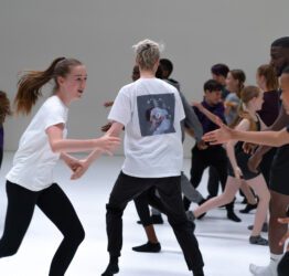 A group of young people moving around a white space.